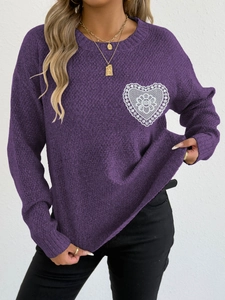 Detalle del aplique de corazón de encaje blanco y tejido grueso en el suéter morado