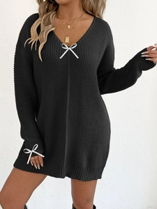 Detail shot of black V-neck knit dress featuring white decorative ribbon bows on sleeve