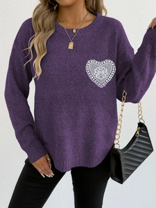 Detalle de jersey de punto morado con un parche de encaje blanco en forma de corazón