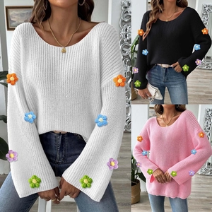 Detail von bunten 3D-Häkelblumen an langen Schlagärmeln dieses Damen-Strickpullovers