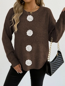Détail d'appliqués de fleurs 3D sur un pull en maille marron à manches longues femme