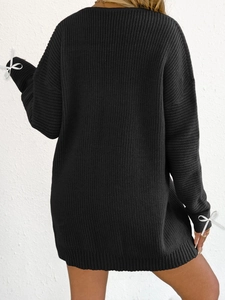 Oversized black ribbed knit sweater dress with white ribbon bows on the cuffs