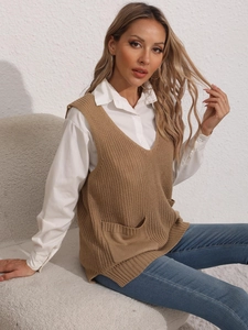 Women's brown V-neck knit vest with front pockets over white shirt and denim jeans