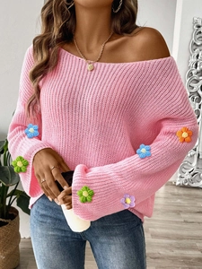 Detail eines rosa Strickpullovers mit 3D-Häkelblumen an ausgestellten Ärmeln und Carmen-Ausschnitt