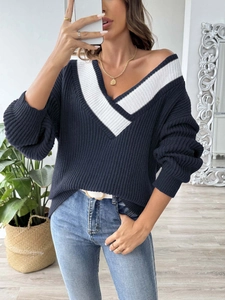 Détail du col en V oversize avec bordure contrastée blanche sur un pull en maille bleu marine