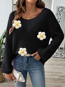 Detailed knit texture of black sweater featuring 3D white and yellow crochet daisies