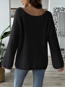 Detail of oversized black knit sweater featuring a stylish back V-neck and bow embroidery