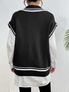 Dettaglio del gilet nero in maglia stile college con strisce bianche sull'orlo posteriore