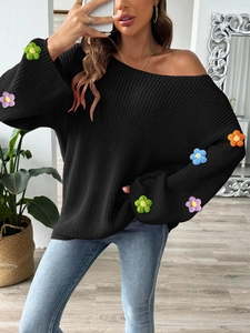 Detailansicht des schwarzen Strickpullovers mit bunten Häkelblumen am Ärmel
