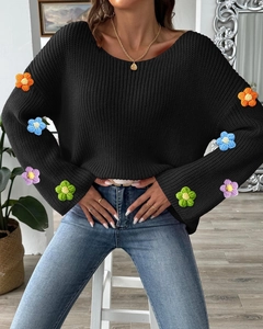 Nahaufnahme bunter Häkelblumen an den Ärmeln des schwarzen Rippstrickpullovers