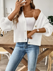Détail d'un cardigan blanc en maille ajourée montrant les boutons ambrés élégants