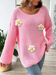 Close-up of pink knitted sweater featuring 3D crochet daisy patches and thick texture