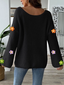 Detailansicht handgefertigter 3D-Häkelblumen an den Ärmeln eines schwarzen Strickpullovers