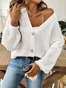 Détail du cardigan en maille ajourée blanche avec boutons ambrés et col en V profond