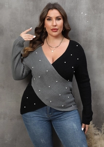 Detail of color-block knit sweater with faux pearl embellishments and V-neckline texture