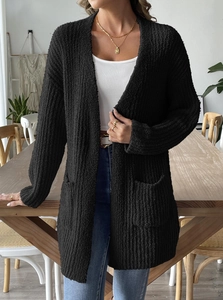 Detail of black knit cardigan with textured popcorn yarn and functional front patch pockets