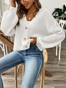 Gros plan sur le gilet en maille épaisse blanche avec boutons marron et texture tissée