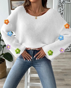 Detail der bunten 3D-Häkelblumen am weißen Strickpullover mit ausgestellten Ärmeln