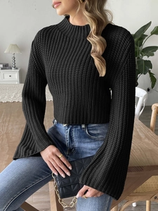 Detail of black chunky knit crop sweater with bell sleeves and mock neck texture