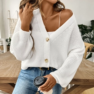 Détail du cardigan blanc en maille épaisse avec boutons ambrés et texture ajourée élégante