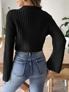 Rear view of a black chunky knit cropped sweater with flared sleeves and a high collar