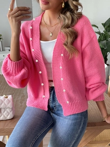 Detailed texture of pink knit cardigan with white pearl button accents and ribbed fabric