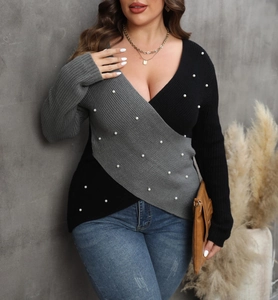 Detail of elegant wrap-style sweater with contrast patchwork and white pearl accents