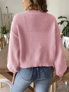 Women's pink knit sweater with blue jeans shown from a back view in a modern home setting