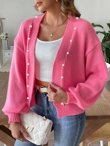 Detail of pink knit cardigan featuring decorative pearl buttons and soft ribbed cuffs