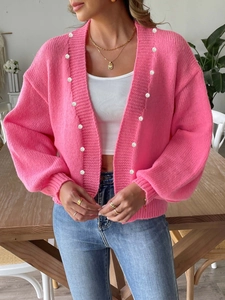 Detailed view of pink knitted cardigan with elegant pearl buttons and textured weave