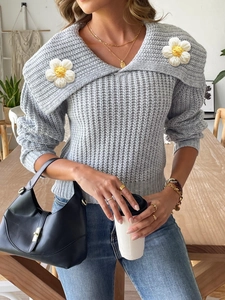 Close-up of grey chunky knit sweater with large collar and crochet daisy flower details