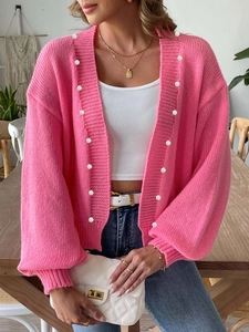 Close-up of pink knit cardigan with elegant white pearl button details and soft knit texture