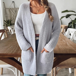 Detail of soft knit cardigan texture with front pockets in a cozy indoor setting