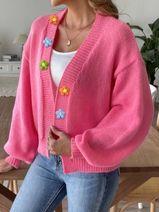Detail of pink knitted cardigan featuring 3D handmade crochet flowers and soft texture