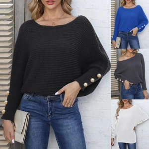 Detail of woven batwing sleeves with elegant gold pearl buttons on a knit sweater