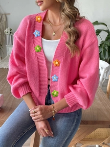 Detail of colorful hand-crocheted floral appliques on pink knit cardigan for women