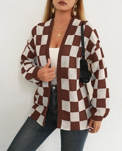 Dettaglio del cardigan in maglia a scacchi marrone e bianco con polsini a costine e vestibilità ampia