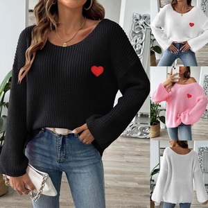 Close-up of heart embroidery on knit sweater featuring ribbed cuffs and neckline