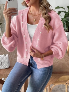 Close-up of pink knit cardigan with white pearl button details and ribbed cuffs