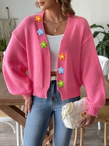 Detail of pink knitted cardigan featuring colorful 3D handmade crochet flower patches