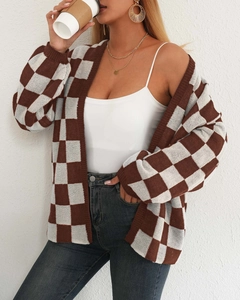 Dettaglio del cardigan in maglia a scacchi marroni e bianchi con trama e scollo a V