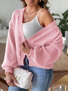 Detail shot of pink chunky knit cardigan featuring decorative white pearl buttons on edges