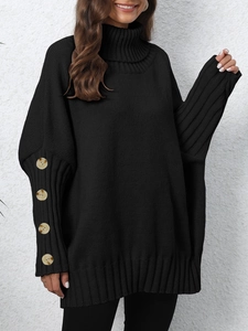 Detail of oversized black turtleneck sweater featuring decorative buttons on ribbed cuffs