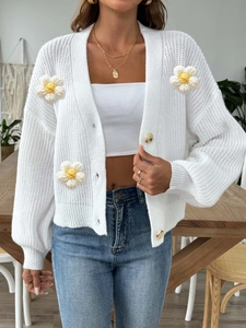 Detailed close-up of handmade crochet flower patterns on white knit cardigan for women