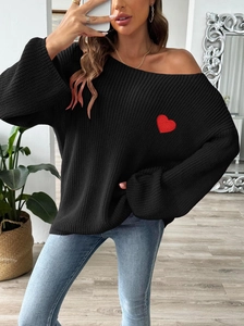 Detail of red heart embroidery on a loose black knit sweater for women