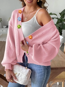 Detail of pink knitted cardigan featuring colorful 3D handmade crochet flowers on front