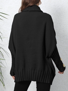 Detail of the oversized black knit sweater featuring ribbed collar and gold button sleeve accents