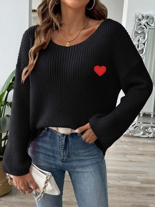 Close-up of black knitted sweater featuring a red heart embroidery patch on the chest
