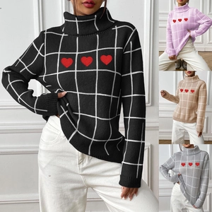 Detail of red heart embroidery and white grid pattern on the high-neck knit sweater