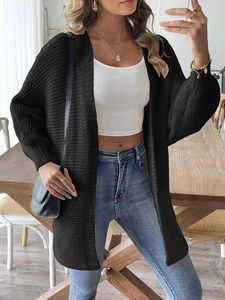 Vue détaillée d'un long gilet en maille noire avec texture côtelée et coupe décontractée